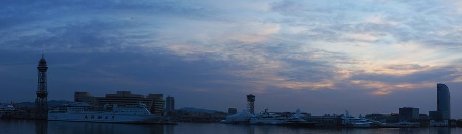 City buildings by sea against sky during sunset