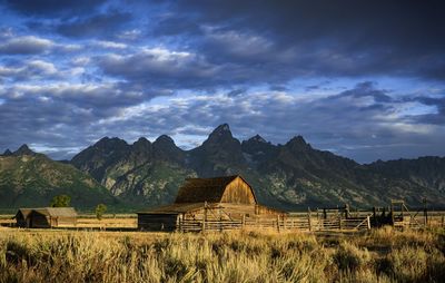 Built structure on field by mountains against sky