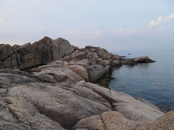 Rock formations on shore against sky