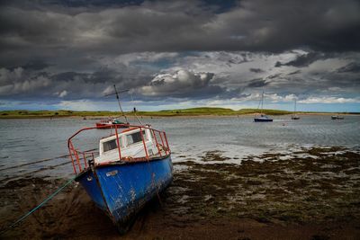 Boat moored on sea shore against sky