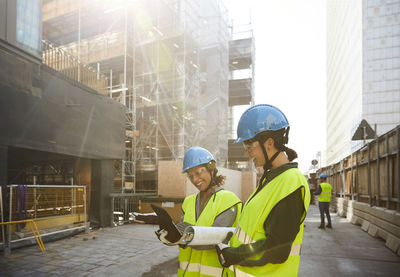 Female engineers discussing over digital tablet at construction site during sunny day