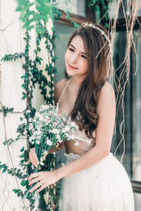 Beautiful young woman standing by flowering plants