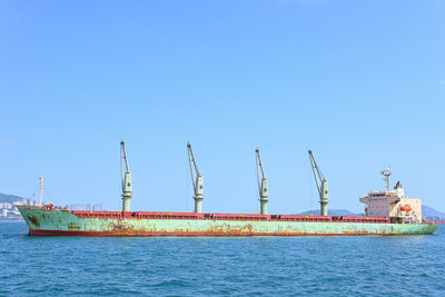 Cranes on bulk carrier ship deck against clear blue sky