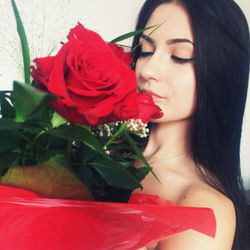 Close-up of young woman with red rose