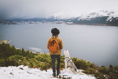 Rear view of woman with dog by river