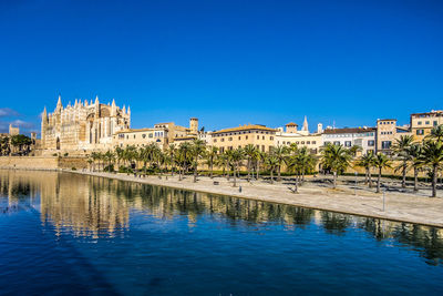 Reflection of building in river against clear blue sky