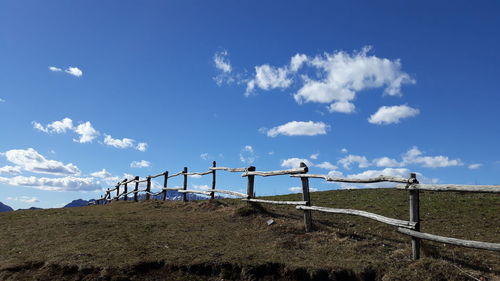 Fence on field against blue sky