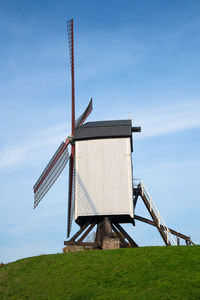 Low angle view of traditional windmill on field against sky