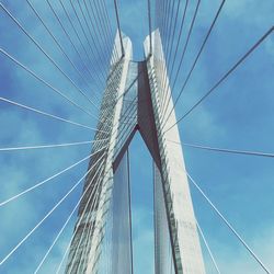 Low angle view of suspension bridge cables against blue sky