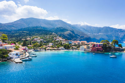 Sailboats in sea by buildings in city against sky