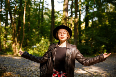Portrait of young woman standing against trees
