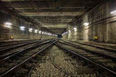 Railroad tracks in illuminated station at night