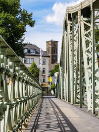 Walkway amidst buildings in city against sky