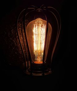 Close-up of illuminated light bulb against black background