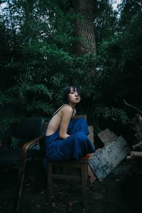 Young woman sitting on tree trunk in forest