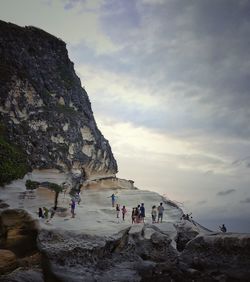 People at rock formation against sky