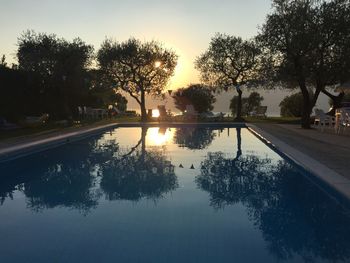 Reflection of trees in water at sunset