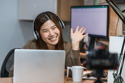 Mid adult woman using mobile phone while sitting on table