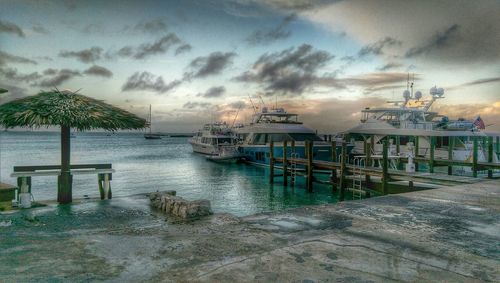 Boats in sea against cloudy sky