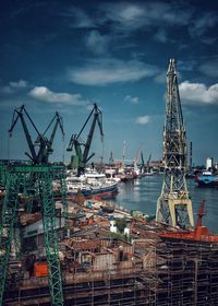 Cranes at commercial dock against sky