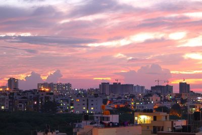 Illuminated buildings against cloudy sky during sunset