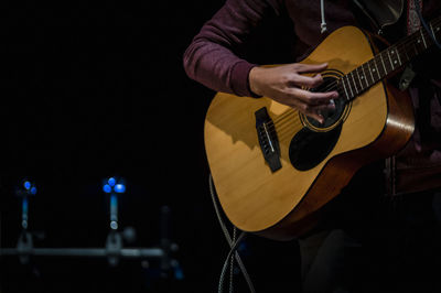 Midsection of musician playing acoustic guitar