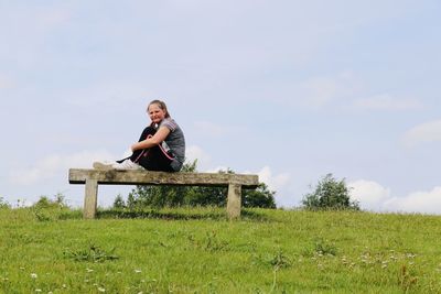 Man sitting on seat in field against sky