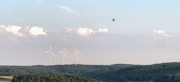 Wind turbines on landscape against sky