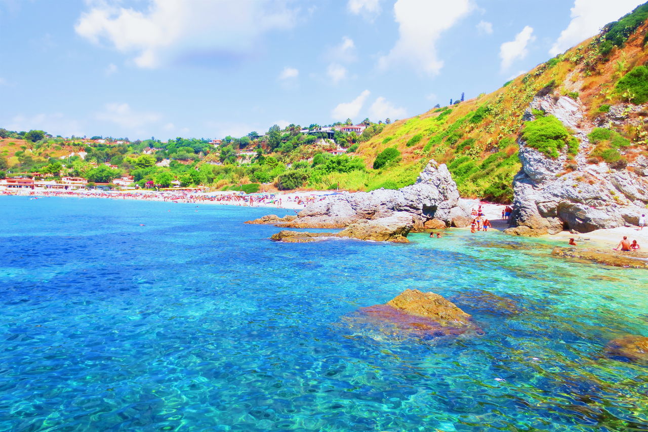 water, sky, tranquility, sea, tranquil scene, scenics, beauty in nature, nature, blue, tree, cloud - sky, rock - object, idyllic, mountain, cloud, day, coastline, turquoise colored, rock formation, outdoors, non-urban scene, remote, green color, no people, growth, grass, plant, landscape, calm