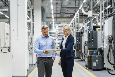 Businesswoman explaining colleague over tablet pc in factory