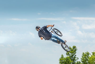 Low angle view of man performing stunt on bicycle against sky