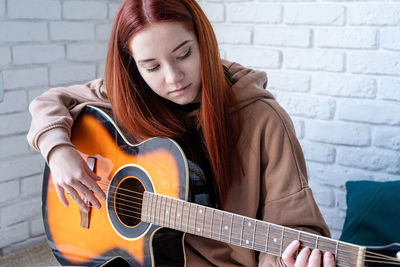 Portrait of young woman playing guitar