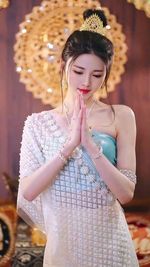 Portrait of young woman standing against wall