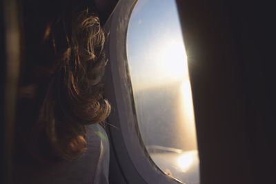 Rear view of woman looking through airplane window