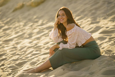 Young woman sitting on sand at beach