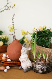 Easter holiday decor. daffodils and hyacinths in a pot, eggs and a rabbit figurine and branches