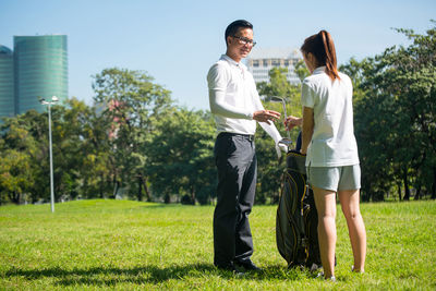 Full length of couple playing golf on field