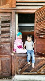 Portrait of smiling girl sitting on door