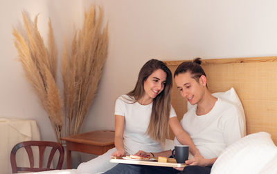 Happy and smiling in love young couple having romantic breakfast in bed in  morning inside a house