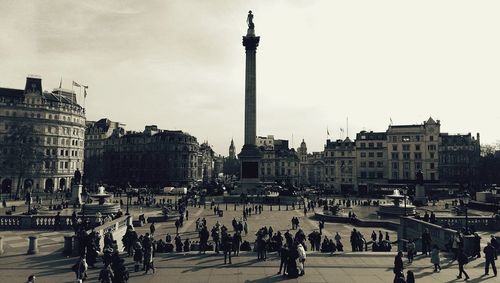 People on city street against cloudy sky