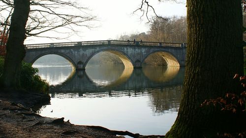Arch bridge over river against clear sky
