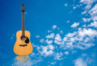 Low angle view of guitar against blue sky
