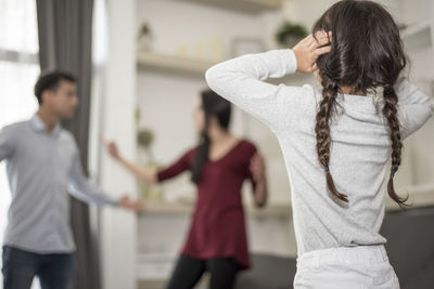 Girl covering ears while parents arguing at home