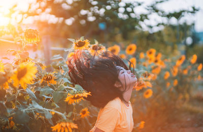 Side view of woman tossing hair in sunflower field