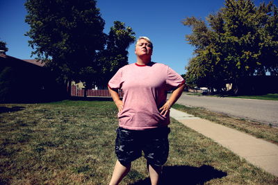 Portrait of confident mature woman standing with hands on hips in backyard