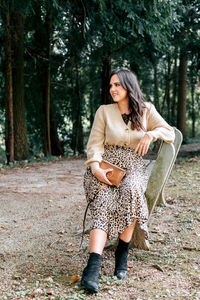 Beautiful young woman sitting on bench in park, autumn, fall, style, fashion.