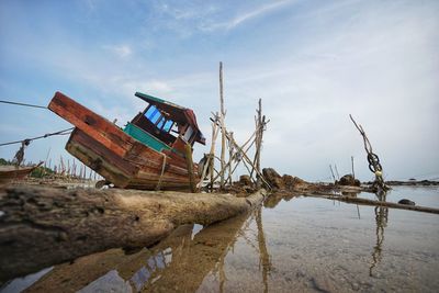 Abandoned boat at beach against sky