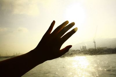 Silhouette of hand on window by water