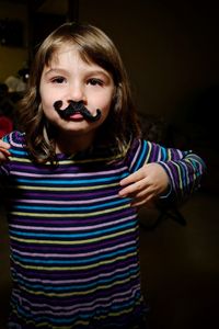 Portrait of girl wearing artificial mustache at home