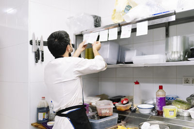 Young male chef checking orders while working in kitchen at restaurant